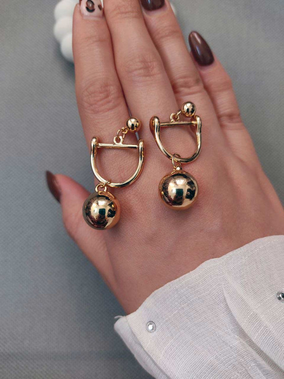 نمای نزدیک گوشواره آویز طلایی رنگ ثابت، طرح نیم دایره و گوی