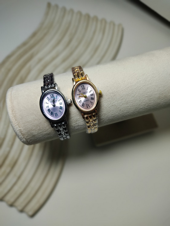 ساعت زنانه صفحه بیضی بند فلزی طلایی و نقره ای روی استند